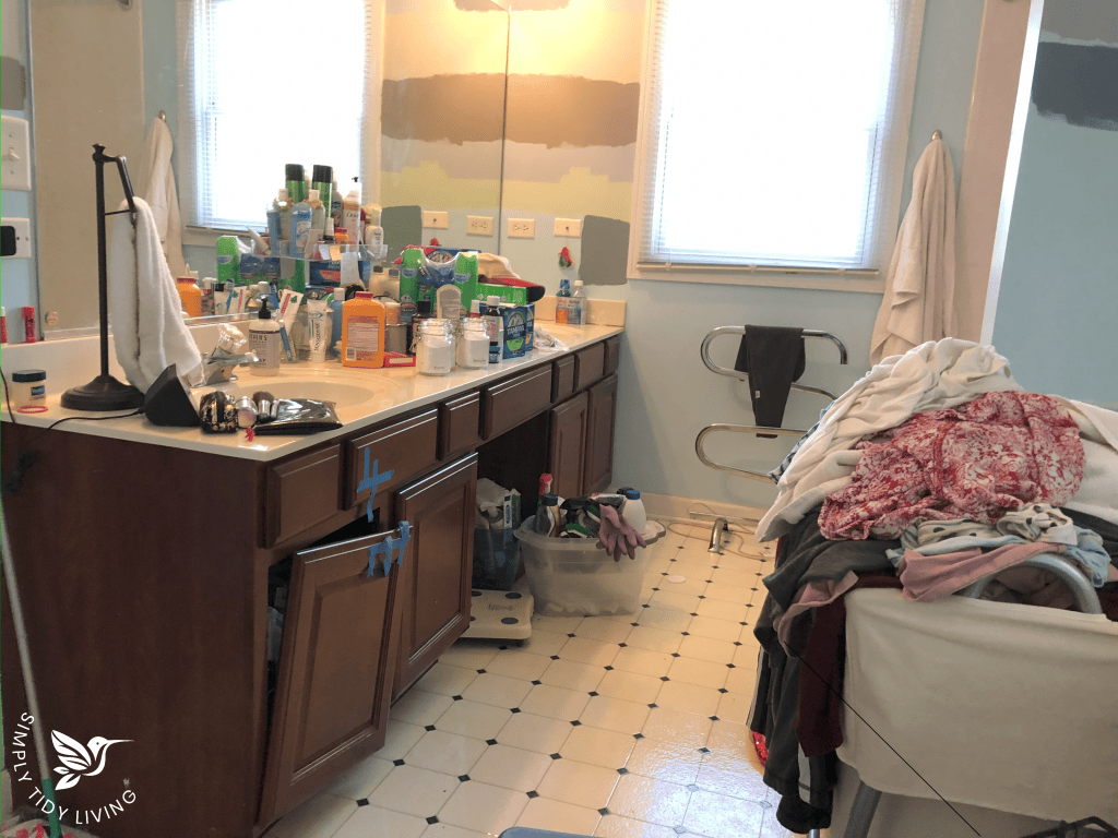 A cluttered bathroom, crowded with dirty clothes and toiletries